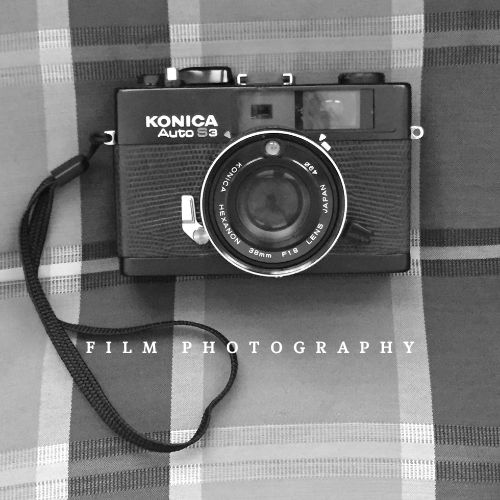 A vintage Konica Auto S3 35mm film camera on a plaid background