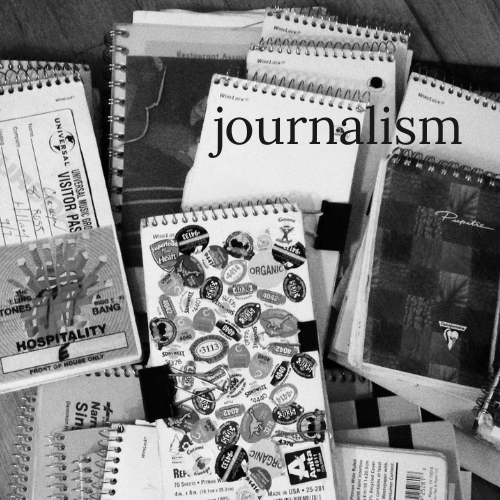 A pile of reporter's notebooks covered in stickers and press passes